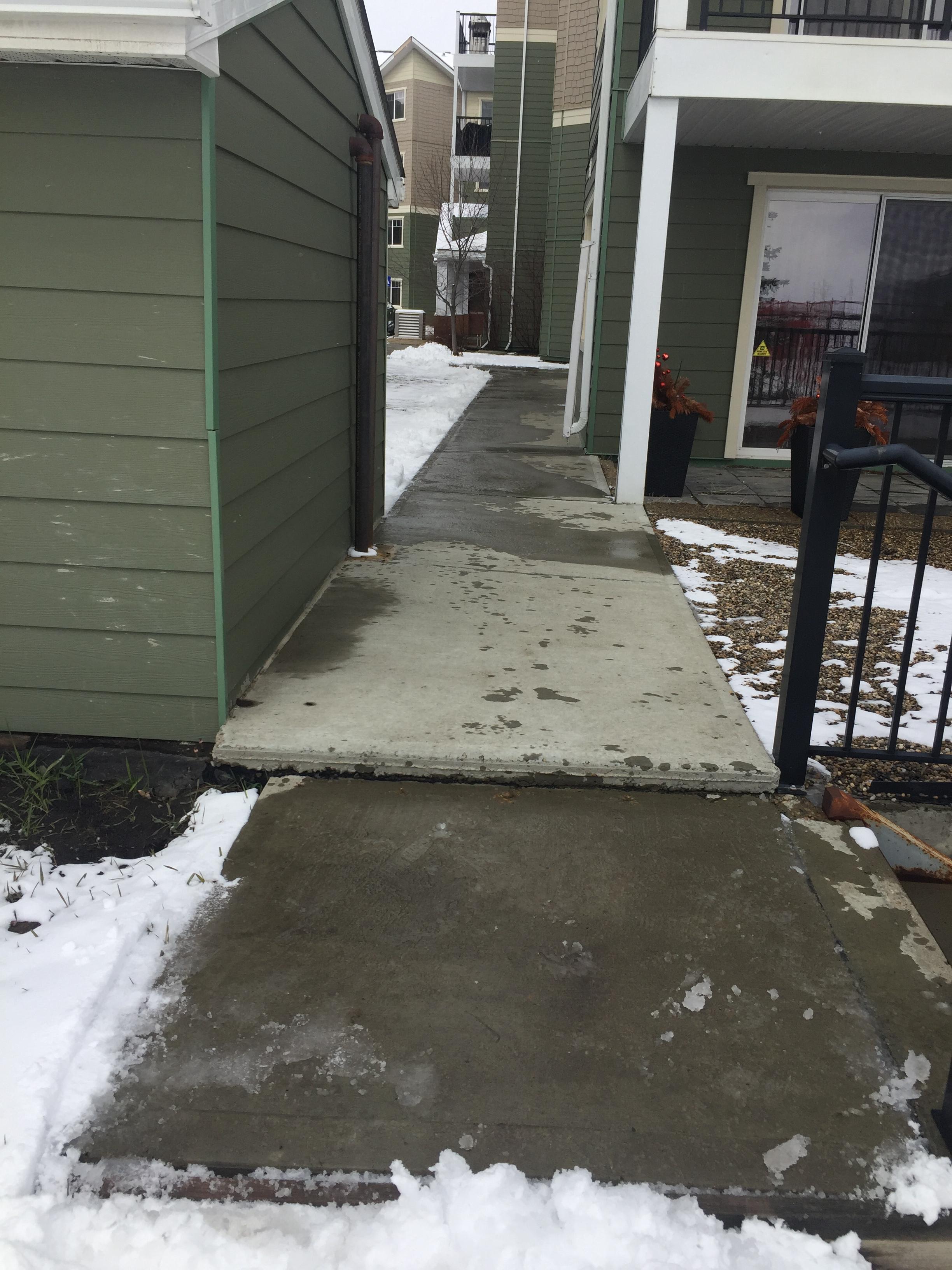 Townhouse pathway cleared alongside green-sided buildings
